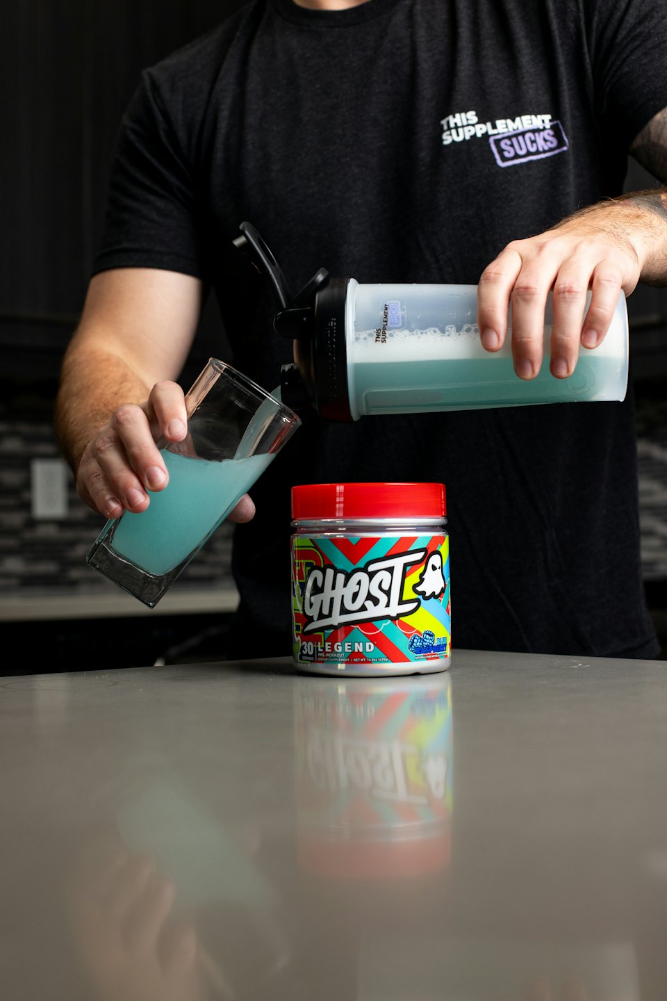 Man pours blue pre-workout from shaker bottle into glass.