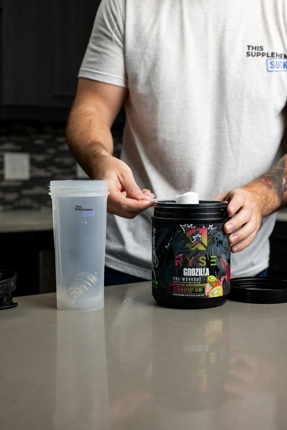 Person scooping pre-workout powder into a shaker bottle.