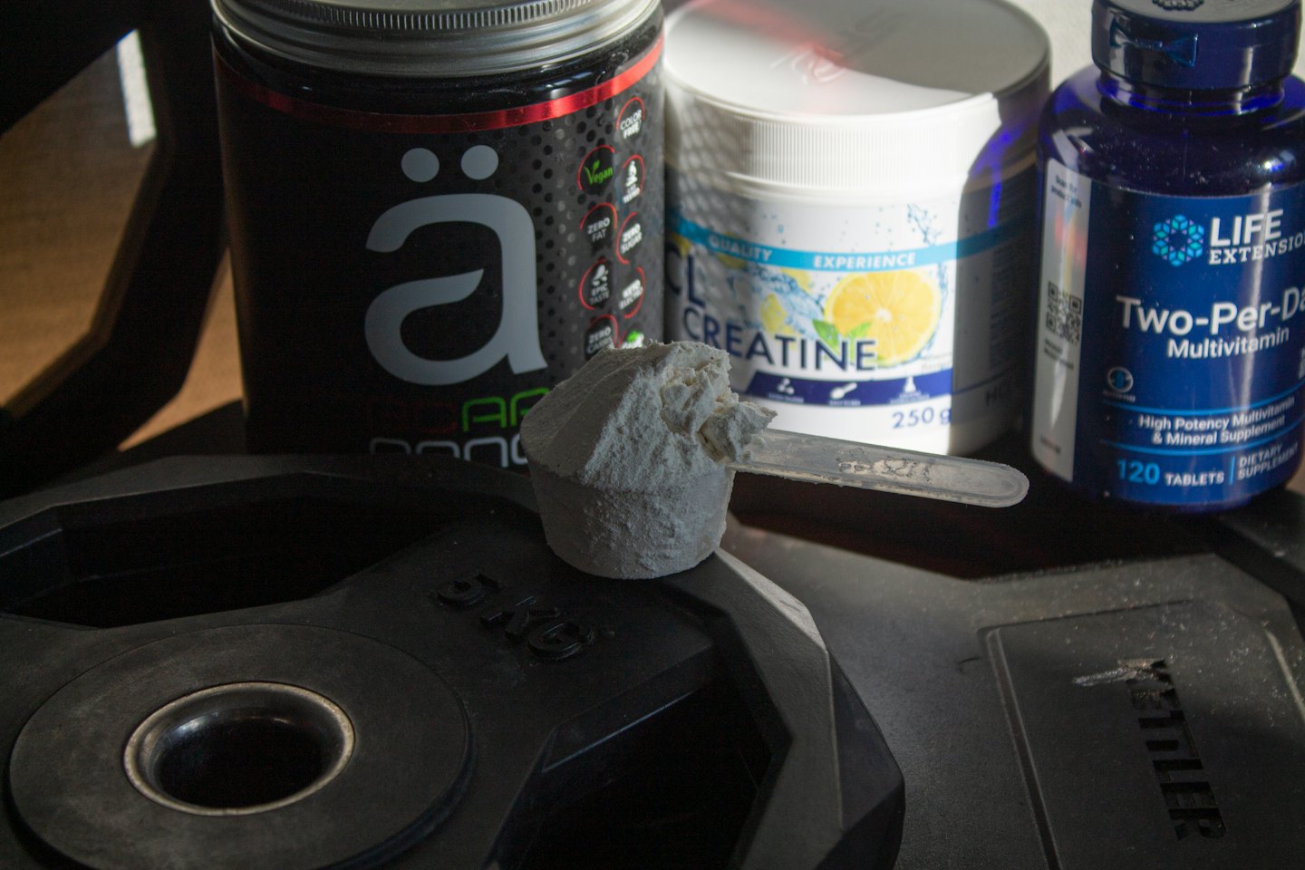 Fitness supplements and a scoop of powder on a weight plate.